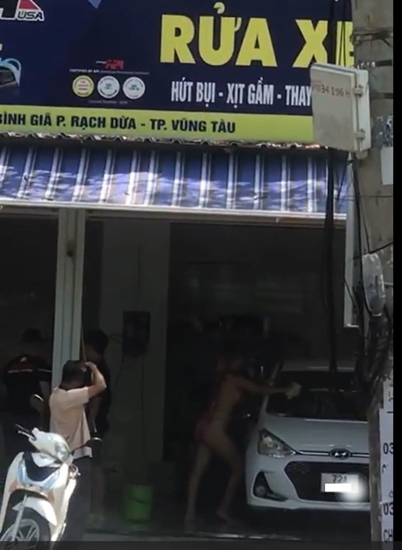 Hình ảnh cô gái mặc bikini rửa xe để chụp hình gây phản cảm. (Ảnh cắt từ clip).
