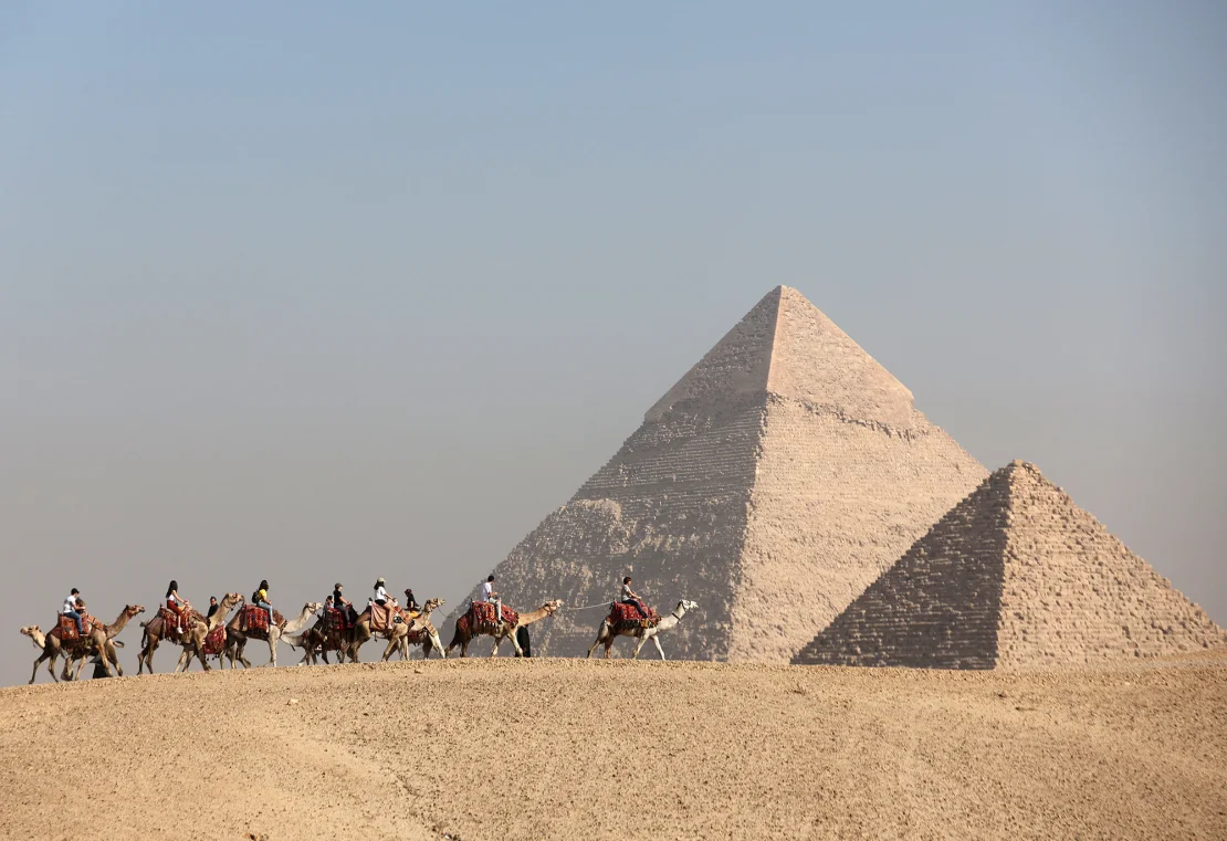 Khách du lịch cưỡi lạc đà trước cao nguyên Kim tự tháp vĩ đại ở Giza, Ai Cập, vào tháng 12. Ảnh: Amr Abdallah Dalsh/Reuters